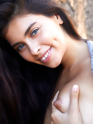 Foxy Alissa takes off her long cardigan and flashes her bare naked physique along the stone wall.